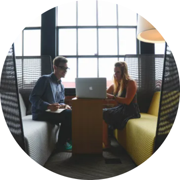 Two people discussing over a laptop in a meeting.